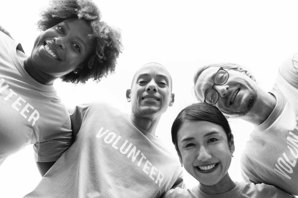 grayscale photography of group of people wearing volunteer printed shirt